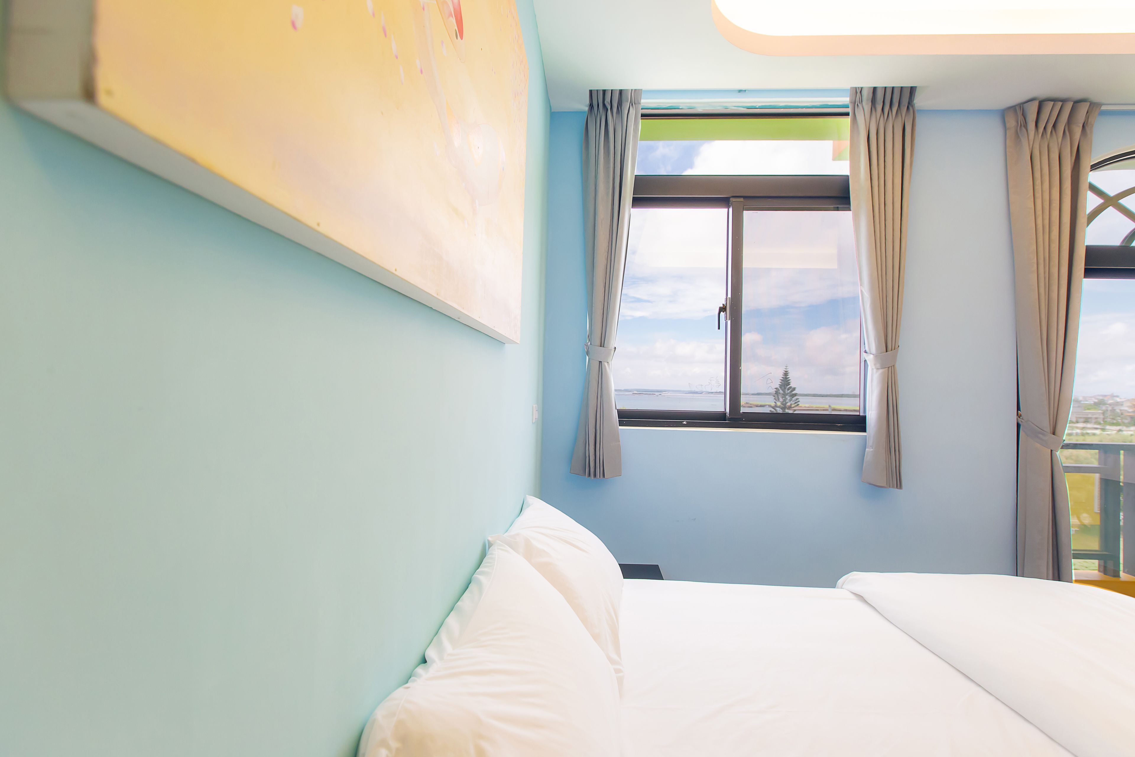 A bedroom with a bed, a window with curtains, and a view of the outside.