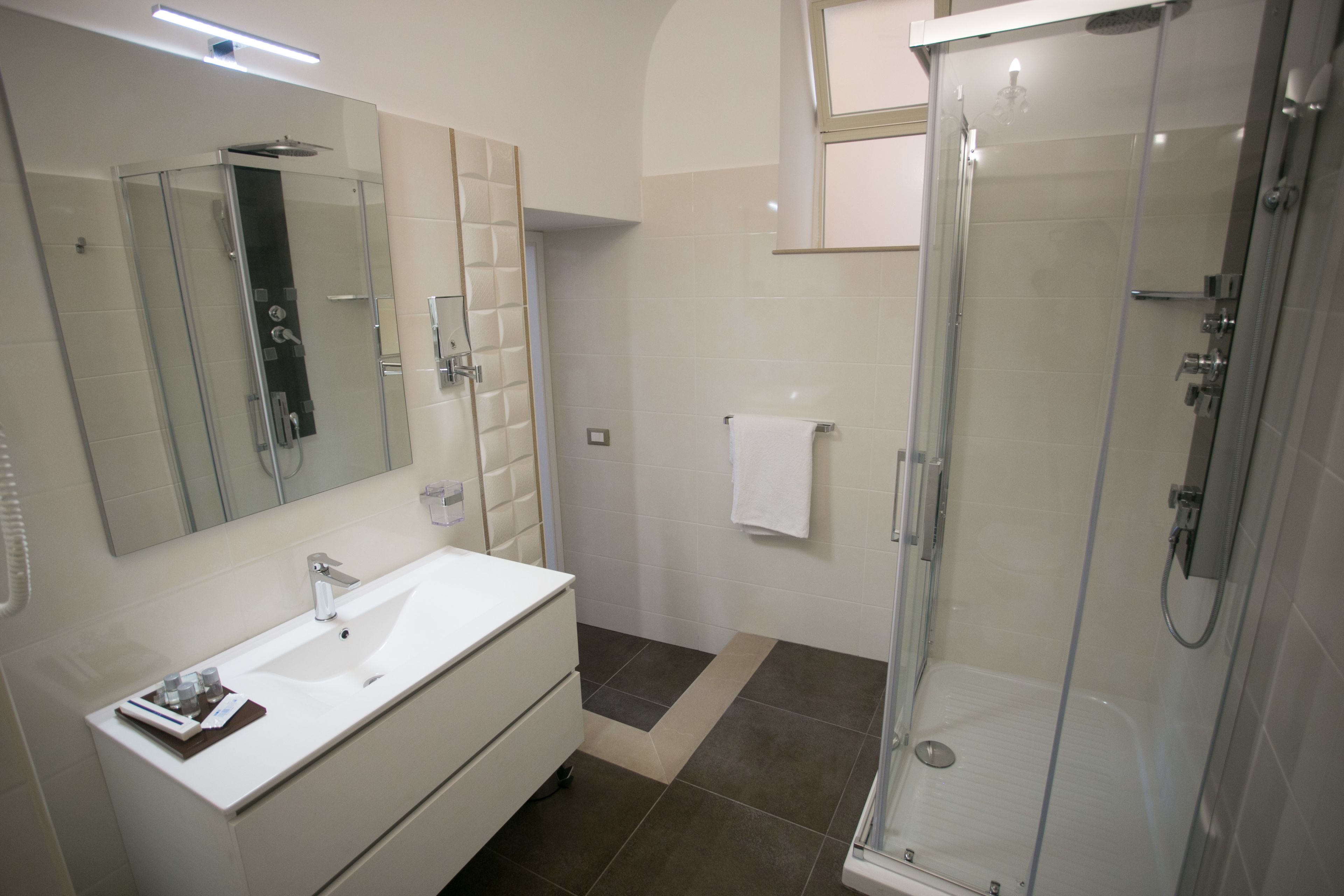 A modern bathroom with a glass-enclosed shower, a white sink, and a large mirror.