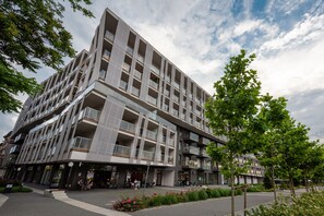 Ein modernes Mehrstöckgebäude mit Balkonen, Außenplätzen und einem angelegten Innenhof.