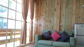 A room with a green sofa, a window with curtains, and a refrigerator. - Blue Pa Hotel (Hengchun)