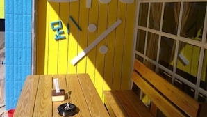 A wooden table and bench set against a yellow wall with the word "Blue" and some Chinese characters. - Blue Pa Hotel (Hengchun)