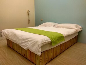 A single bed with a wooden frame, white bedding, and a green throw blanket. - Blue Pa Hotel (Hengchun)