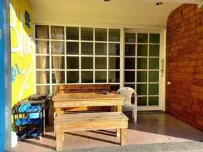 A wooden bench and table set outside a building with a sliding glass door. - Blue Pa Hotel (Hengchun)