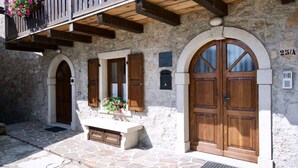 Un bâtiment en pierre avec des portes en bois et un balcon orné de fleurs.