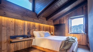 Une chambre à coucher en bois, avec un lit, une table de chevet et une fenêtre donnant sur l’extérieur.