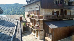 Un bâtiment traditionnel en pierre, doté de balcons en bois et de jardinières fleuries.