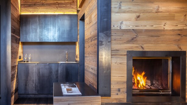 Un intérieur moderne agrémenté d’une cheminée intégrée, de lambris en bois et d’une table minimaliste avec un magazine.