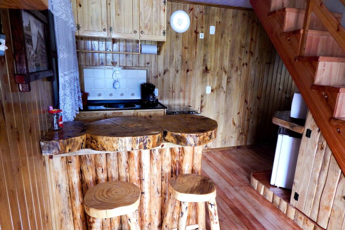 Una cocina rústica con armarios de madera, una isla de madera con taburetes y una escalera de madera.