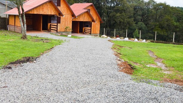 Ein rustikales Holzhaus mit einer Schotterauffahrt zum Eingang.