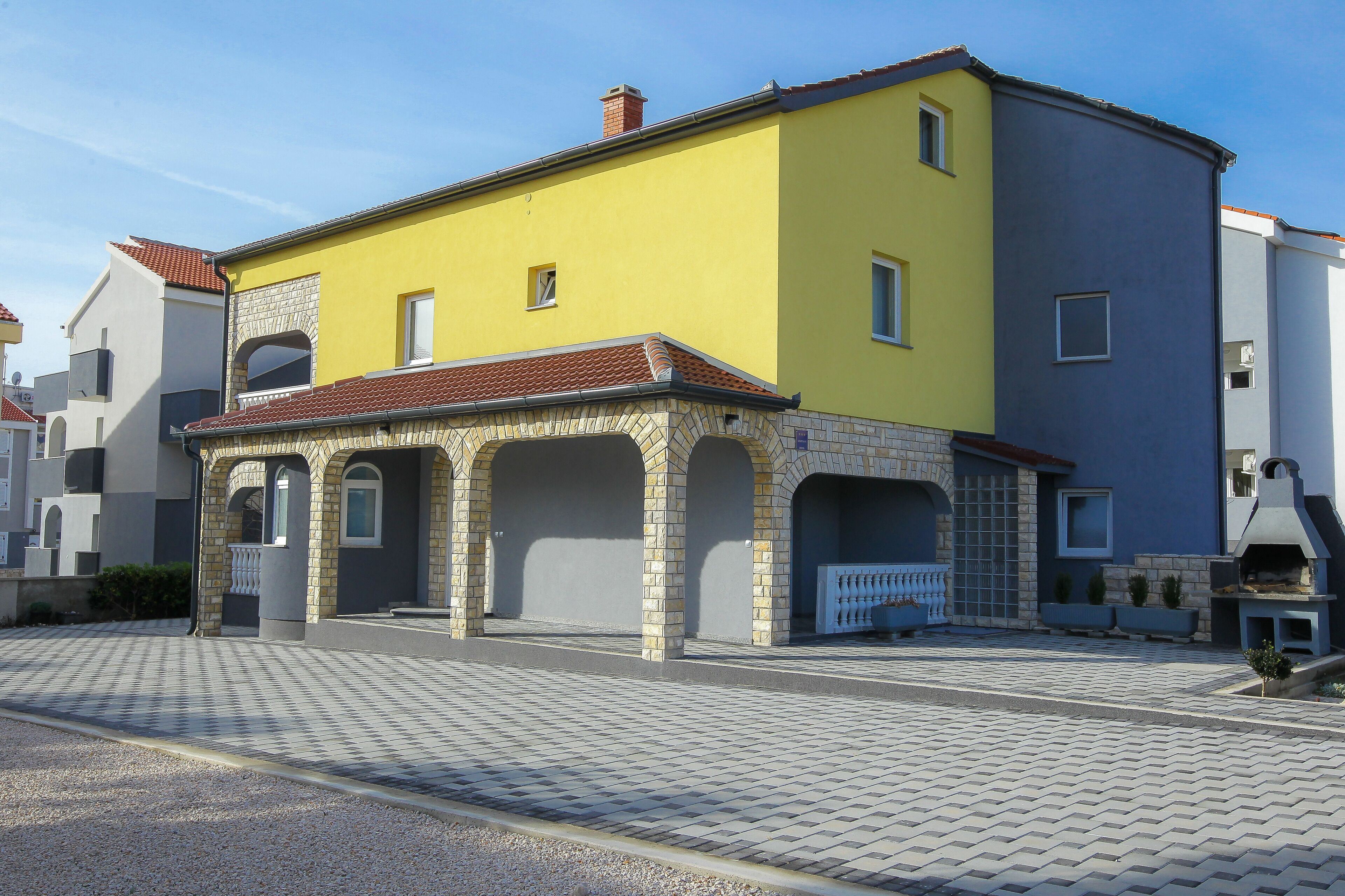 A yellow building with a tiled roof and a small porch area.