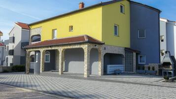 A yellow building with a tiled roof and a small porch area.