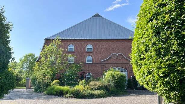Un grand bâtiment en briques, doté d’un toit en pente et de nombreuses fenêtres.
