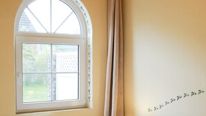 Une chambre à coucher avec un lit, une fenêtre, un radiateur et un mur orné d’un motif décoratif.