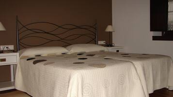 A neatly made bed with a patterned bedspread, two bedside tables with lamps, and a wall-mounted shelf.