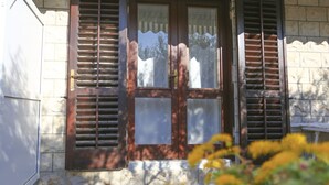 A building with a stone facade, wooden shutters, and a door with glass panels. - Guest House Kovacevic (Hvar)