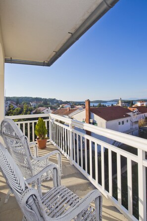 A balcony with white railings, wicker chairs, and a potted plant. - Guest House Kovacevic (Hvar)