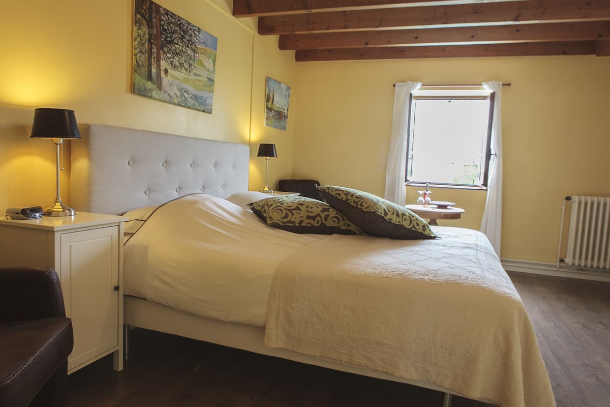 Ein ordentlich eingerichtetes Schlafzimmer mit einem Bett, Nachttischen und einem Fenster.