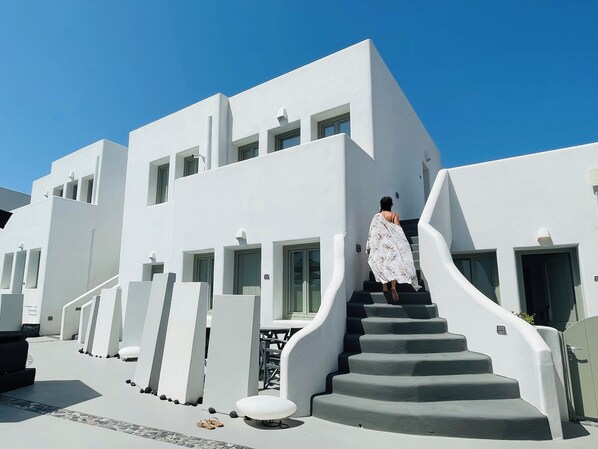 Steps lead up to a door in a modern building with large windows and a flat roof.