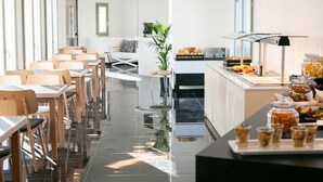 A modern hotel dining area with a long counter, buffet, and seating arrangement. - Kallos Imar Boutique Hotel  (Santorini)