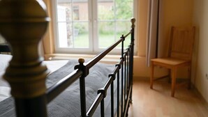 A bedroom with a bed, a window, and a chair. - Ferienwohnung Muschel (Kopendorf auf Fehmarn)