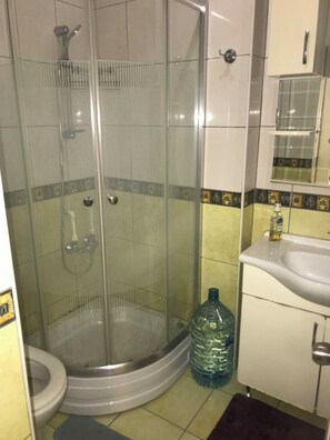 A shower enclosure with a glass door, a toilet, and a sink with a bottle of hand soap. - Luxury and Comfortable Apartment (Istanbul)