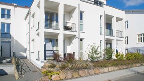 Un edificio residencial moderno de varios pisos con balcones, fachada de piedra y cielo despejado.