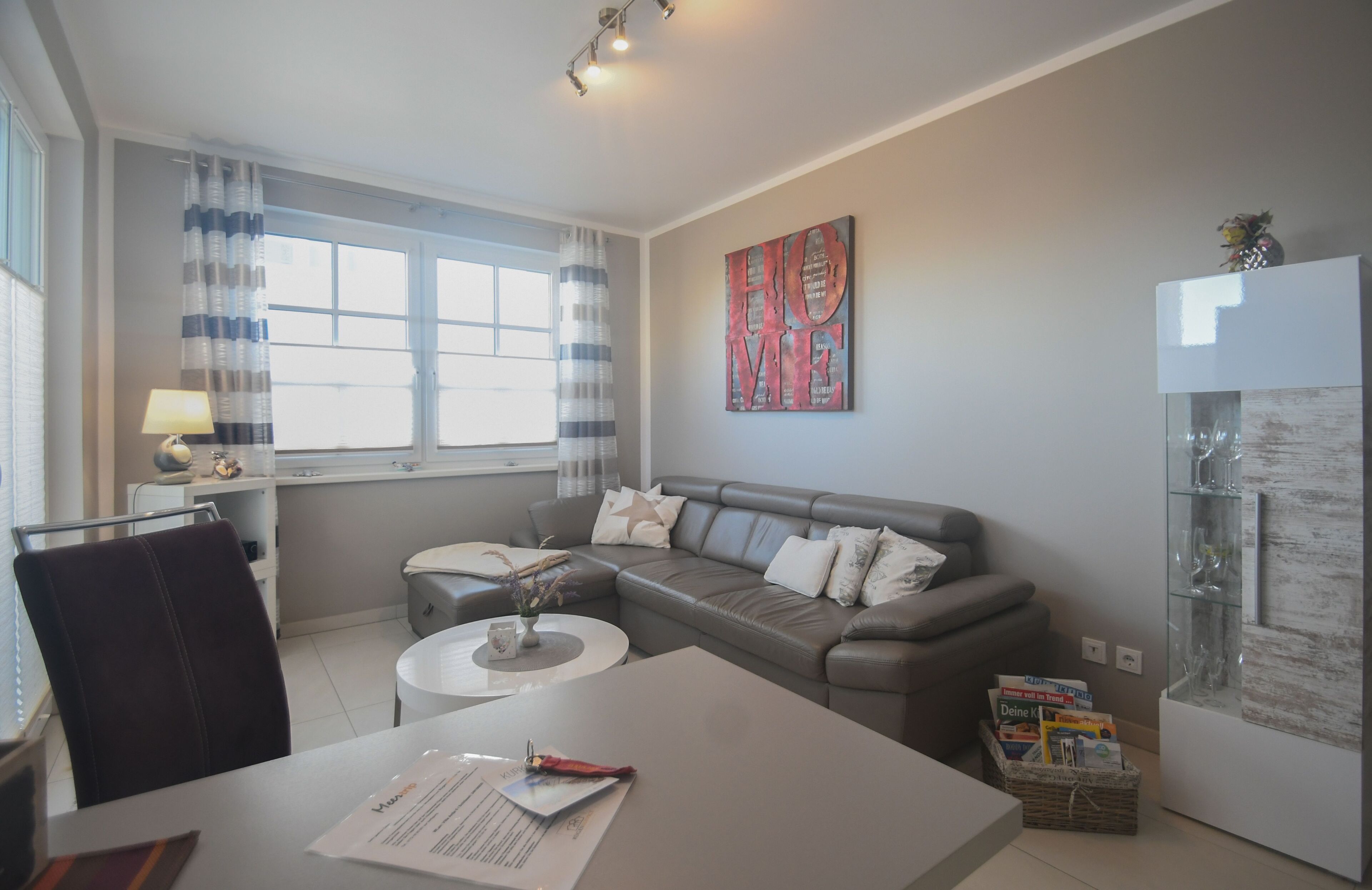 A modern living room with a grey sofa, a coffee table, and a glass cabinet.