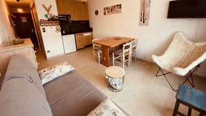 Un ambiente compatto con angolo cottura, zona pranzo, divano e una poltrona soffice.