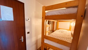 Camera con letto a castello, una porta in legno e un termostato sulla parete.
