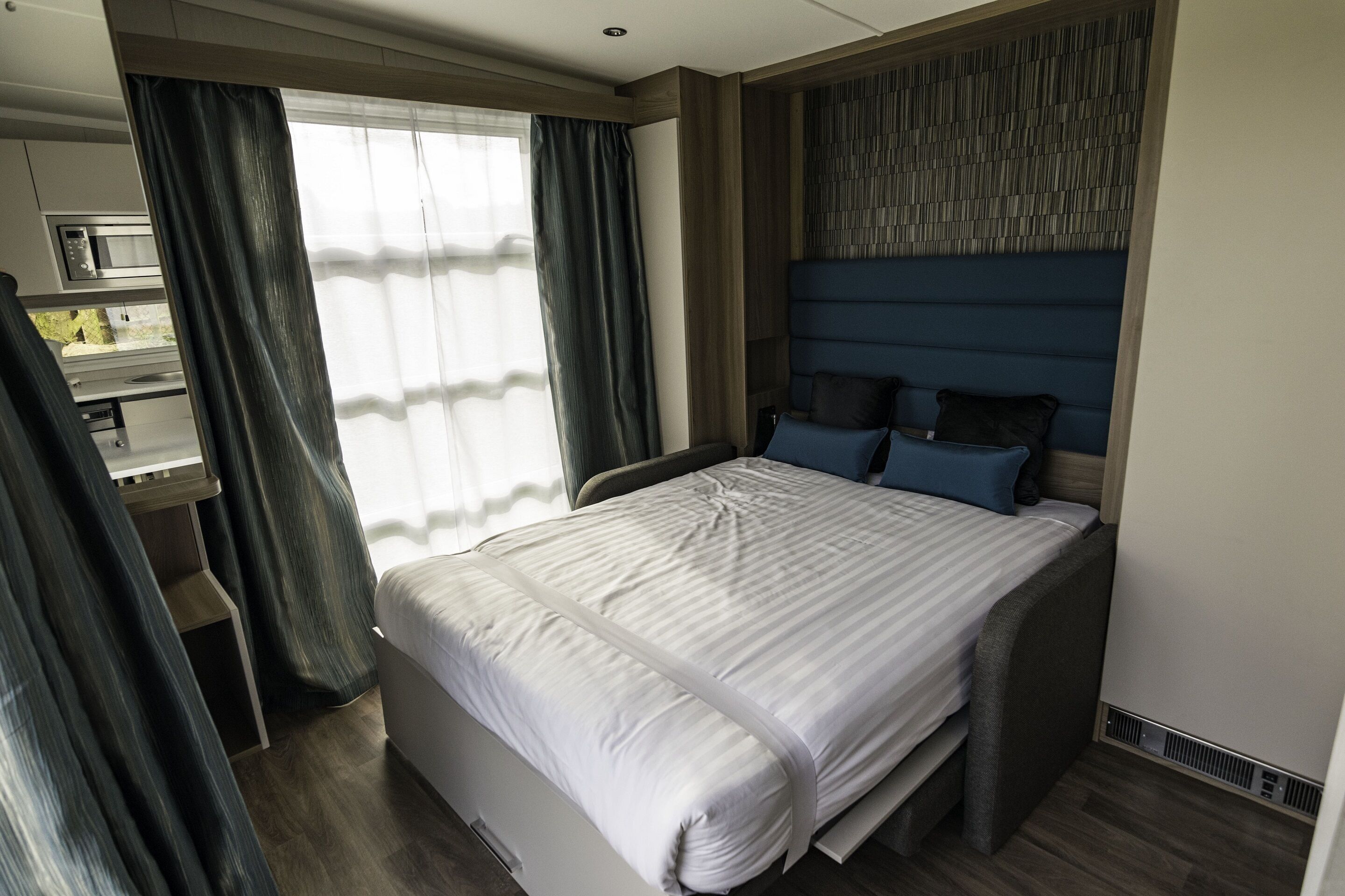 Une chambre d’hôtel moderne, dotée d’un grand lit, d’un bureau et d’une fenêtre avec des rideaux.