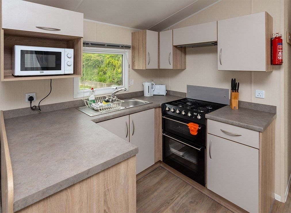 A compact kitchenette with a microwave, stove, oven, and sink.
