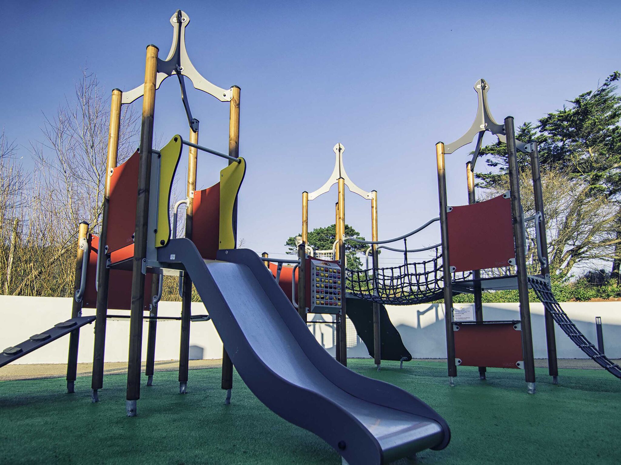 A playground with a slide, climbing structures, and a rope net.