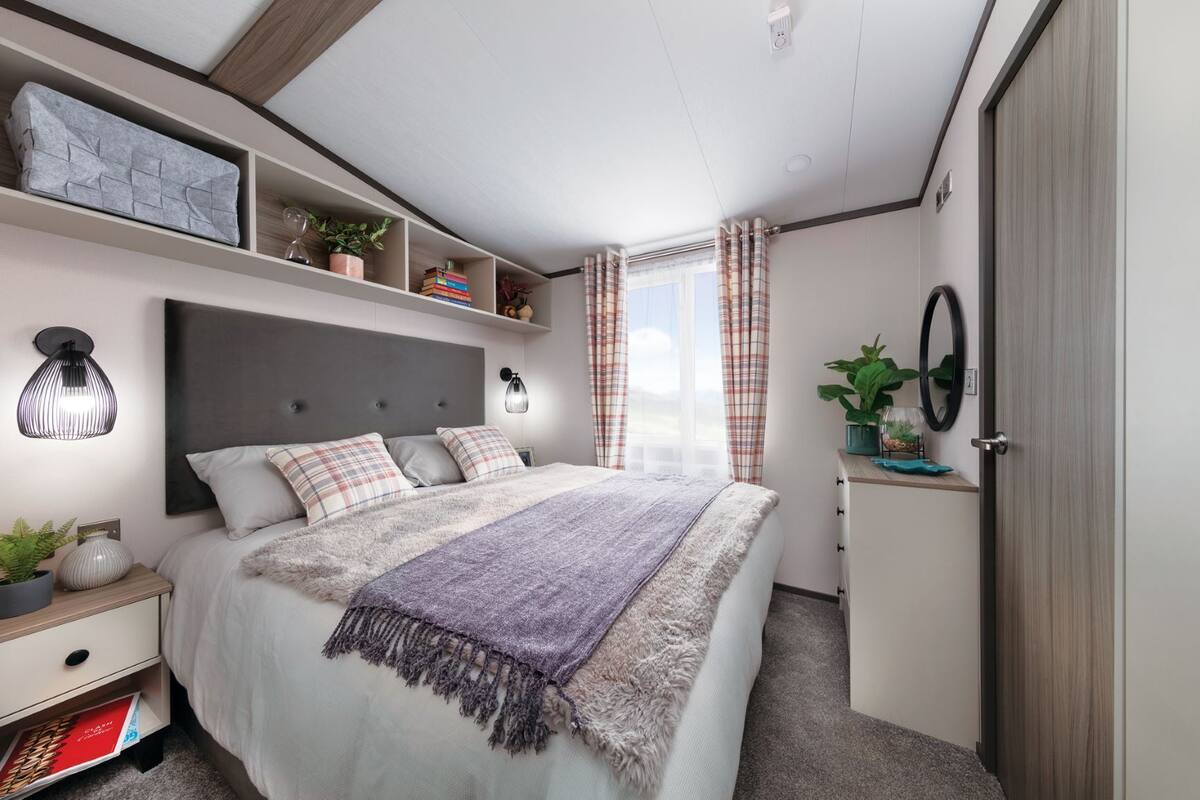 Une chambre à coucher moderne, comprenant un lit, des tables de chevet, une armoire et un luminaire fixé au plafond.