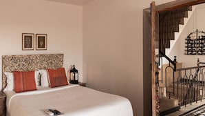 A bedroom with a large bed, a wooden bench, a nightstand, and a staircase with a railing. - The Secret House - Adults Only (Jaisalmer)
