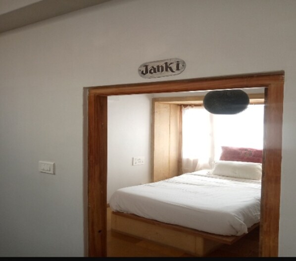 Un dormitorio con cama, un marco de puerta de madera, un interruptor de luz y un cartel sobre la puerta.