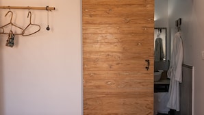 A wooden door leading to a bathroom with a checkered floor, a sink, and a robe hanging on the wall. - The Secret House - Adults Only (Jaisalmer)