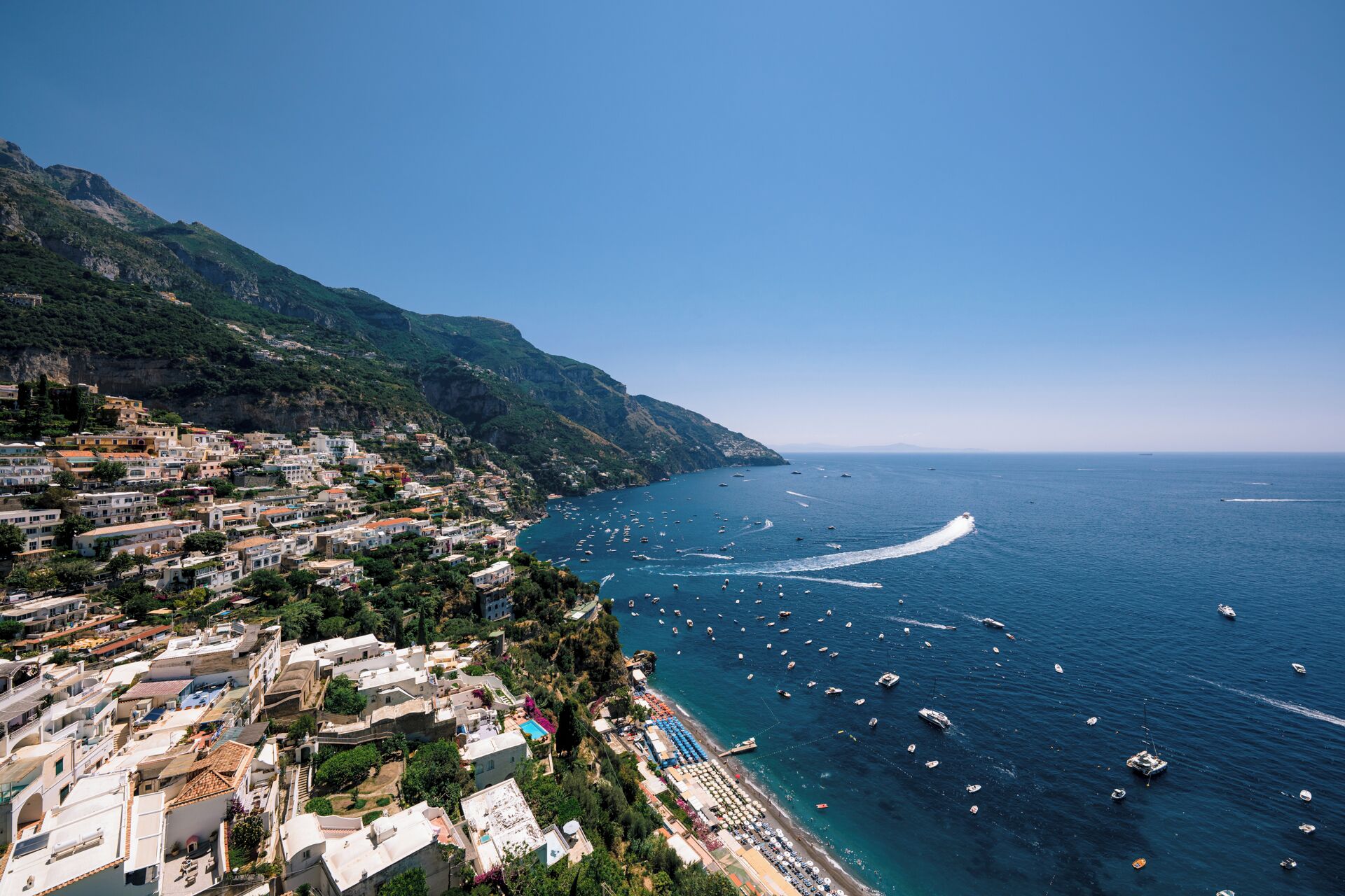 A coastal town with buildings along the hillside and a marina with boats.