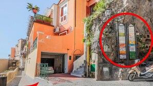 A narrow street with a building featuring a staircase and a scooter parked outside. - Villa Anfitrite (Positano)