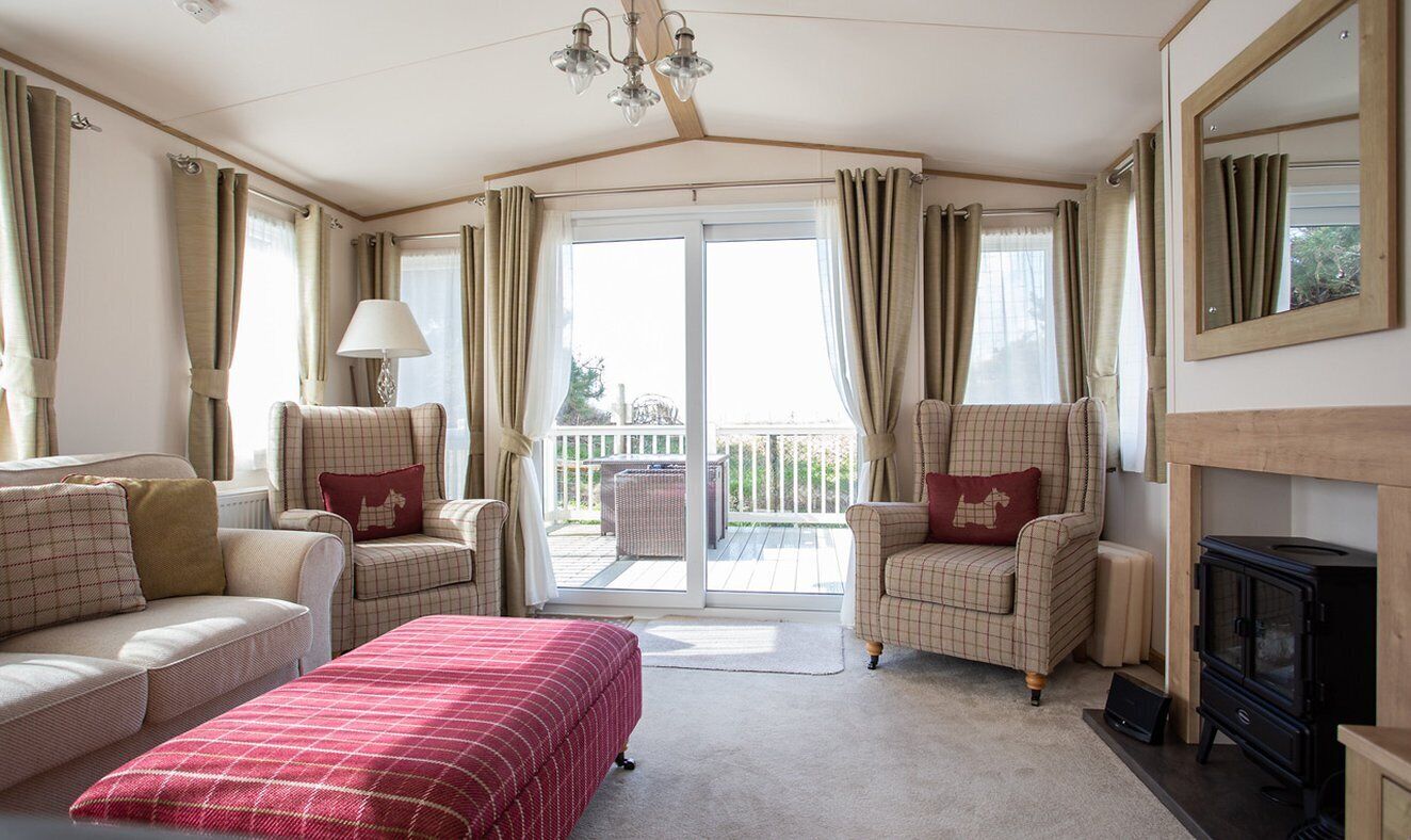 Ein gemütliches Zimmer mit einer Couch, einem Sessel und einem Bett. Ein Kamin und ein großes Fenster mit Vorhängen sind ebenfalls vorhanden.