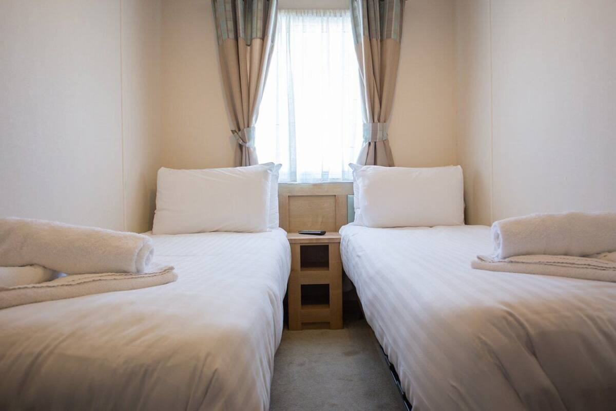 A twin room with two beds, a nightstand, and a window with curtains.