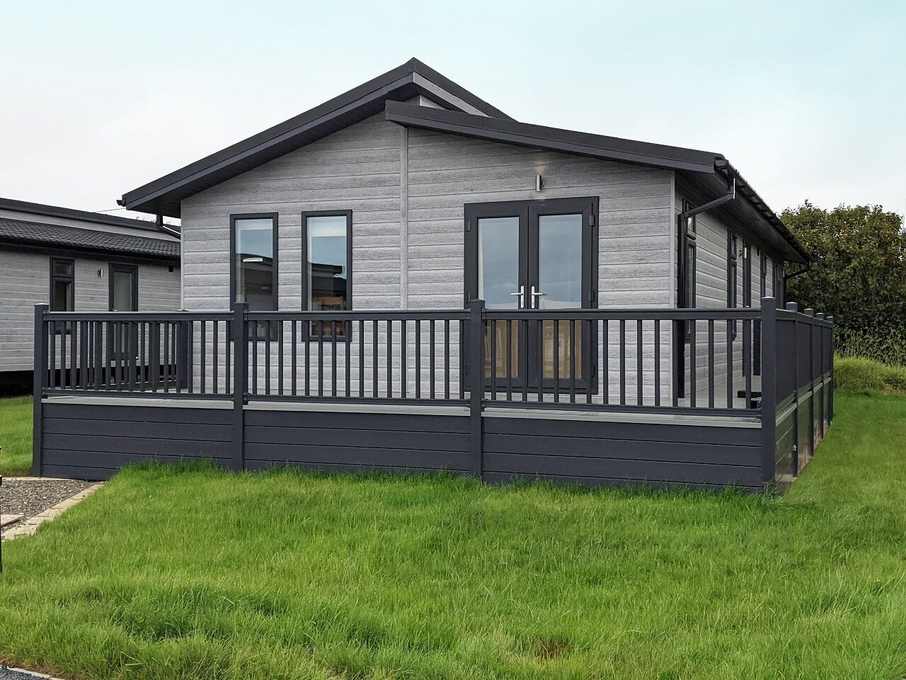 A modern, single-story building with a grey exterior and a dark grey balcony.