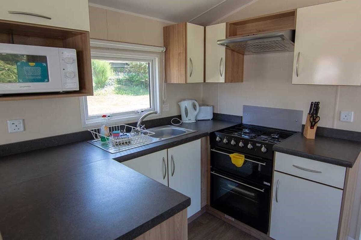 A compact kitchen with a microwave, stove, sink, and cabinets.