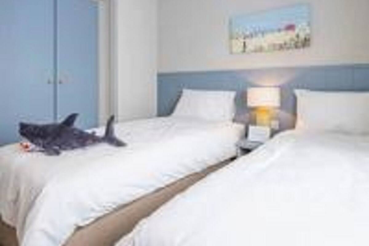 A hotel room with two beds, a nightstand, a lamp, and a painting on the wall.