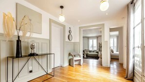A spacious living area with wooden flooring, a modern console table, and a large mirror.