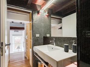 A modern bathroom with a large white sink, two dark-colored soap dispensers, and a mirror above the sink. - Trastevere Luxury Loft, unique, modern and with an Italian art gallery (Roma)