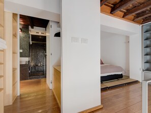 A modern bedroom with a bed, a wooden floor, and a bathroom with a shower. - Trastevere Luxury Loft, unique, modern and with an Italian art gallery (Roma)
