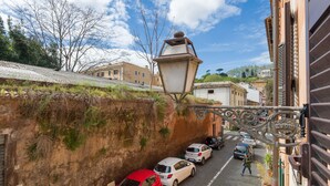 A narrow cobblestone street with parked cars and a pedestrian. - Trastevere Luxury Loft, unique, modern and with an Italian art gallery (Roma)