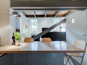 A modern kitchen with a central island, a staircase leading to a loft, and a view of the outdoors. - Trastevere Luxury Loft, unique, modern and with an Italian art gallery (Roma)