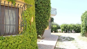 Un bâtiment avec un chemin de pierre menant à une entrée fermée par un portail, entouré de verdure et sous un ciel dégagé.