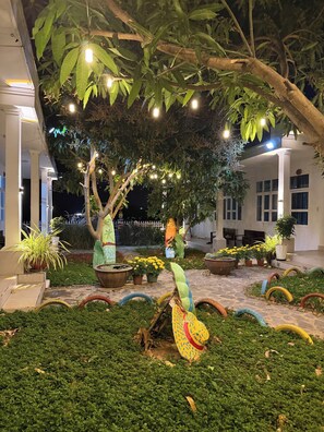 A courtyard with a tree, potted plants, and a colorful sculpture.